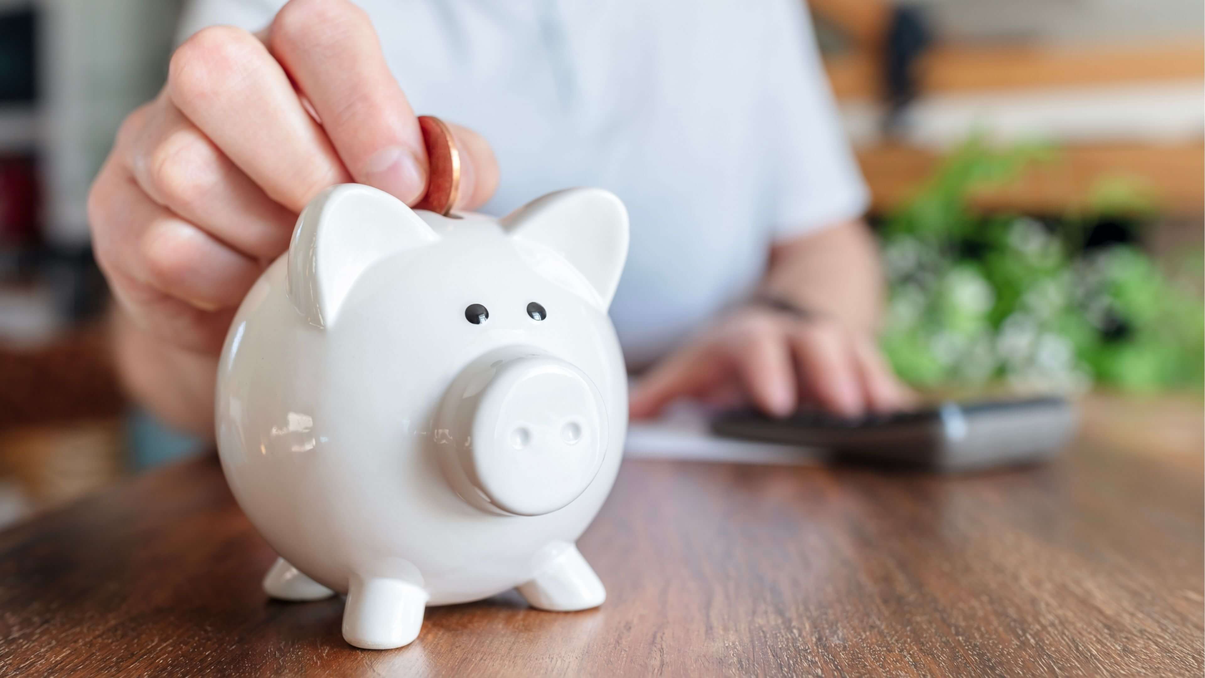 Man putting a coin into a pink piggy bank concept for savings
